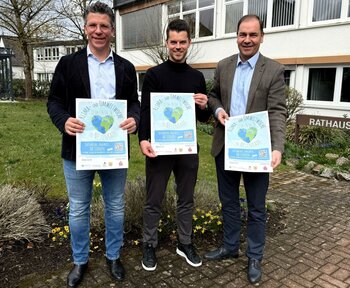 Bürgermeister Volker Klüter, Klimaschutzmanager Simon Mai und Tomislav Majic, Leiter der Unternehmenskommunikation der Vereinigten Sparkasse im Märkischen Kreis, bewerben die Klima- und Umweltwoche.