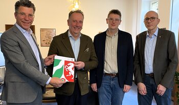Bürgermeister Volker Klüter (v.l.) nahm den Förderbescheid von Thomas Sommer von der Bezirksregierung entgegen. Dabei waren Bauamtsmitarbeiter Richard Schwartpaul und Bauamtsleiter Marcus Henninger. 